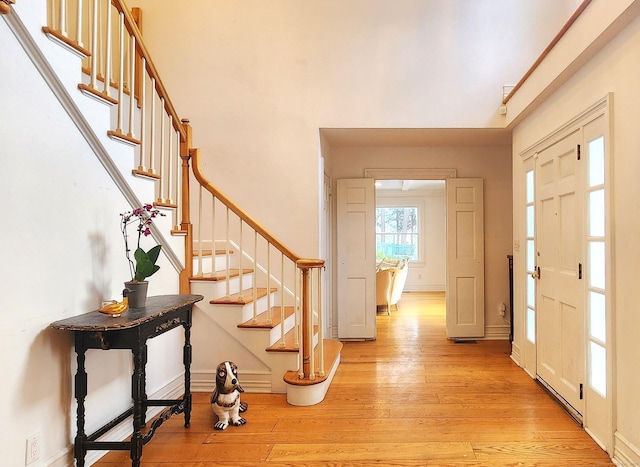 entrance foyer with stairway, baseboards, and light wood finished floors