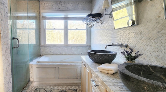bathroom featuring a sink, a garden tub, a stall shower, and double vanity