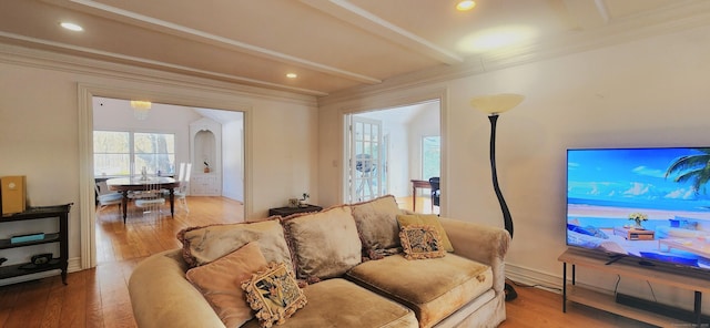living area featuring beam ceiling, ornamental molding, and wood-type flooring