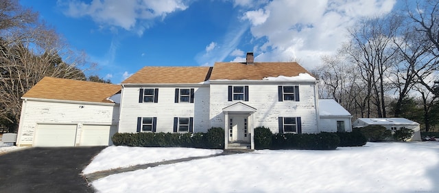 colonial house with driveway and a chimney