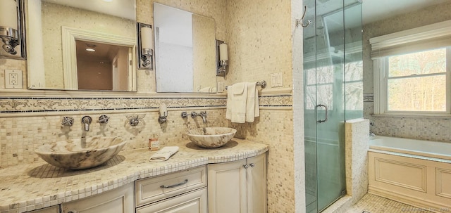 full bath with a sink, a garden tub, double vanity, and a shower stall