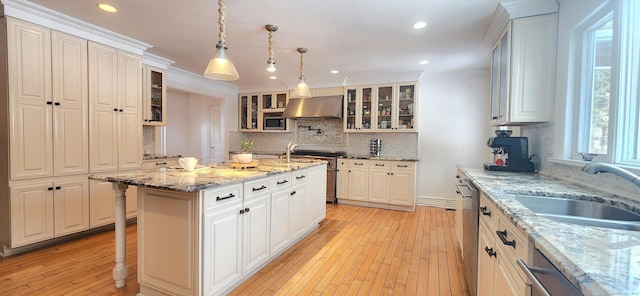 kitchen featuring under cabinet range hood, stainless steel appliances, light wood-style floors, and a sink