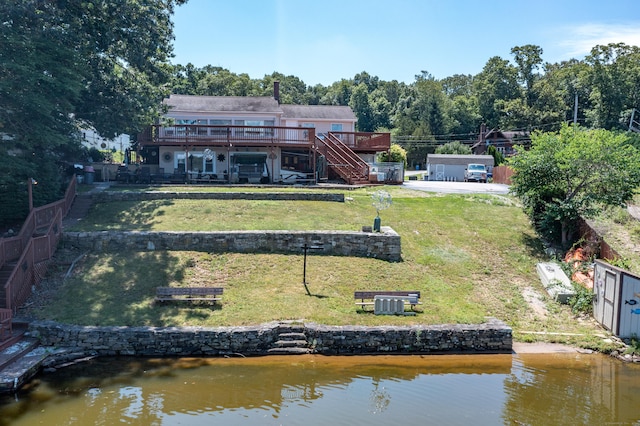 rear view of property featuring a lawn and a deck with water view