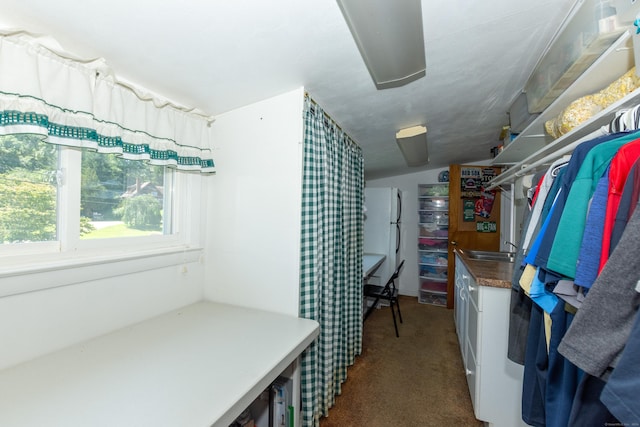 walk in closet featuring dark colored carpet, lofted ceiling, and sink