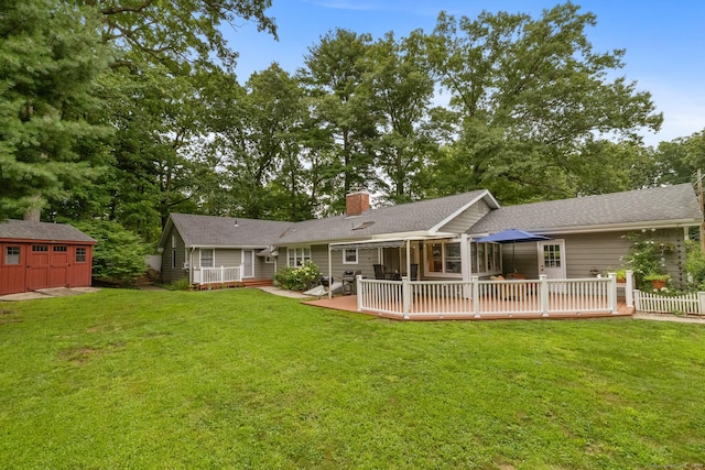 back of property featuring a wooden deck, a lawn, and a shed