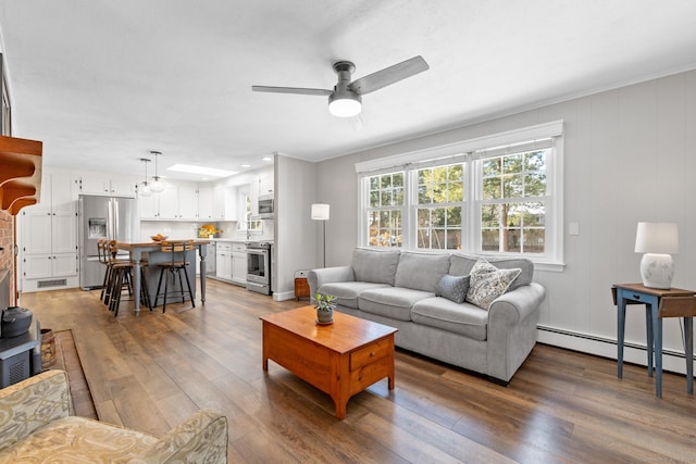 living room with ceiling fan, hardwood / wood-style floors, and a baseboard heating unit