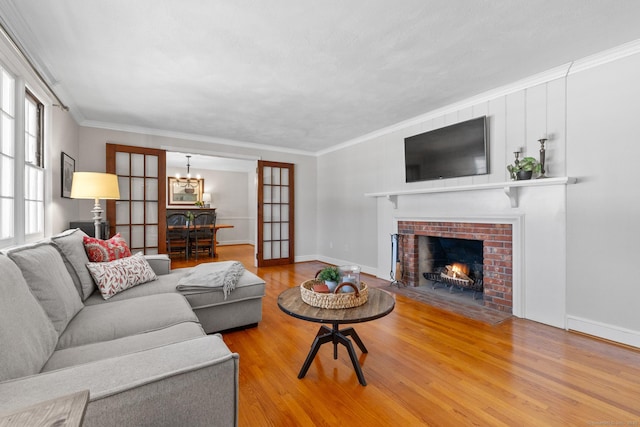 living room with crown molding, a chandelier, hardwood / wood-style floors, and a fireplace