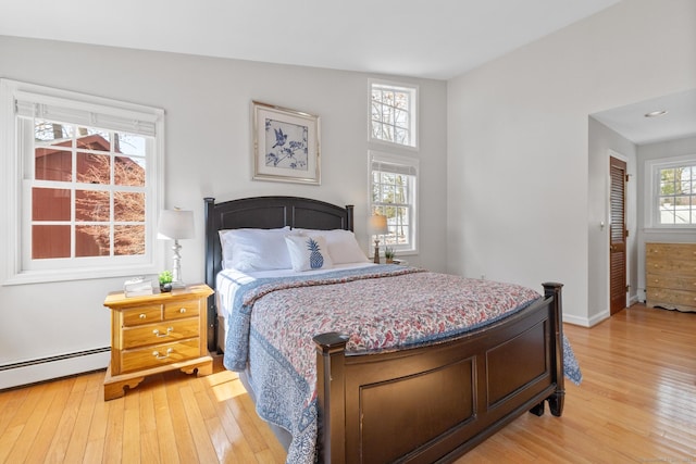 bedroom with baseboard heating and light wood-type flooring