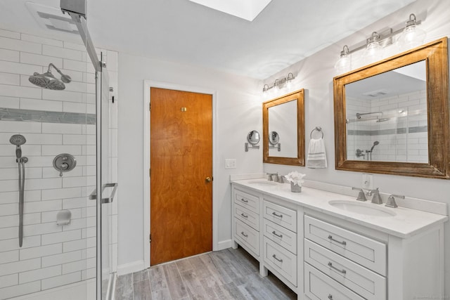 bathroom featuring a shower with door, vanity, hardwood / wood-style floors, and a skylight