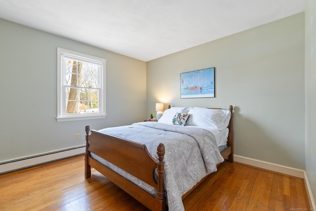 bedroom featuring a baseboard heating unit and hardwood / wood-style floors