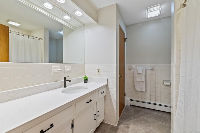 bathroom featuring tile patterned flooring, vanity, a baseboard heating unit, and tile walls