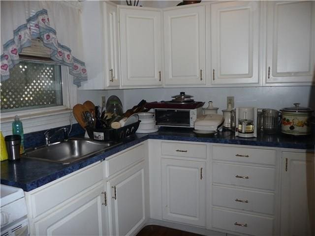 kitchen featuring sink, white cabinetry, and range