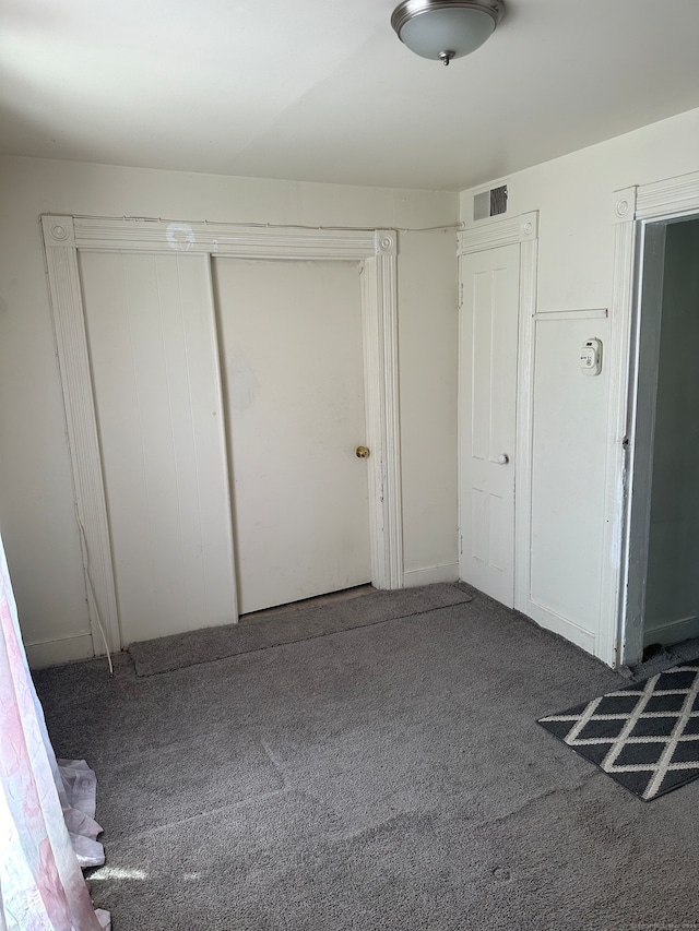 unfurnished bedroom featuring dark colored carpet and a closet