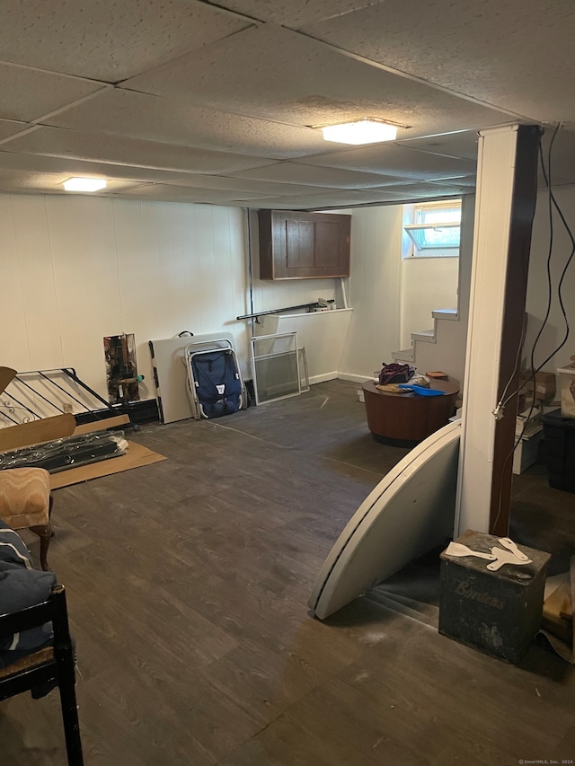 basement with a paneled ceiling and dark hardwood / wood-style flooring