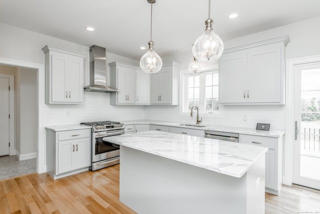 kitchen with wall chimney range hood, appliances with stainless steel finishes, plenty of natural light, and backsplash