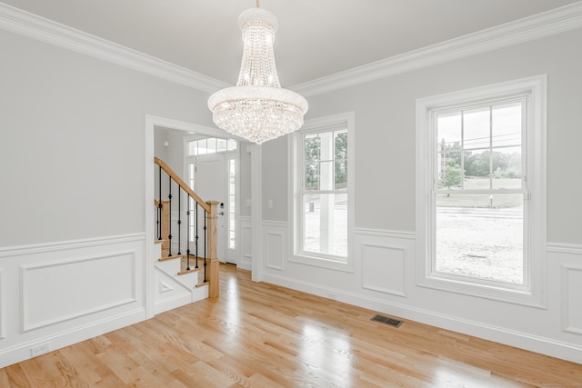 unfurnished dining area featuring a chandelier, crown molding, and light wood-type flooring