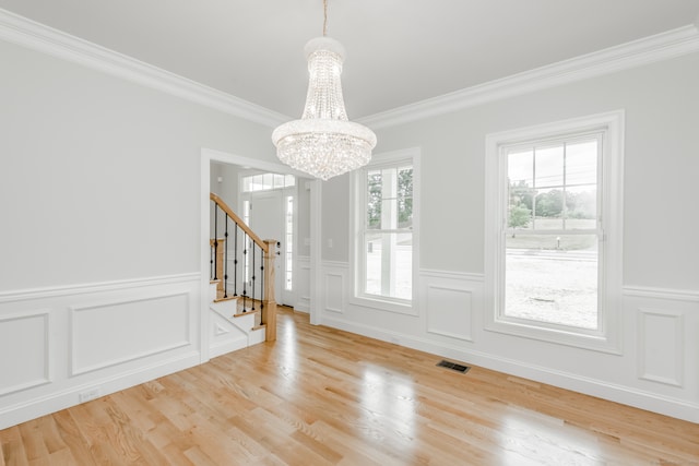 unfurnished dining area featuring an inviting chandelier, light hardwood / wood-style floors, and ornamental molding