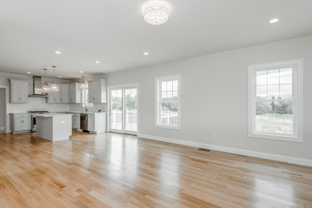 unfurnished living room featuring a chandelier, sink, and light wood-type flooring