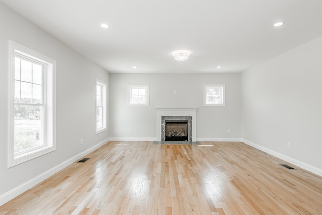 unfurnished living room featuring a fireplace, light hardwood / wood-style flooring, and a wealth of natural light