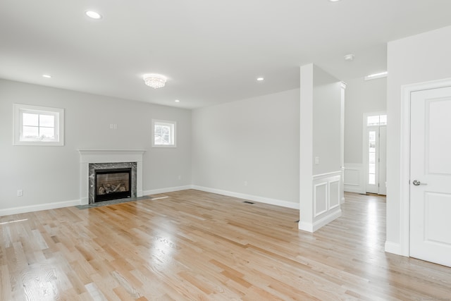 unfurnished living room featuring light hardwood / wood-style floors and a high end fireplace