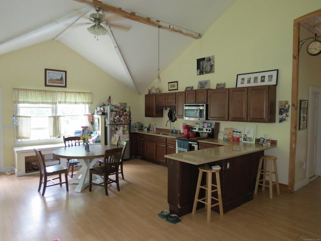 kitchen with a breakfast bar, sink, kitchen peninsula, stainless steel appliances, and light hardwood / wood-style flooring