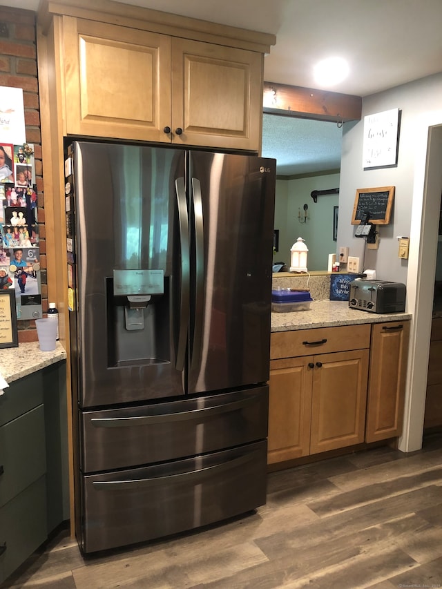 kitchen featuring fridge with ice dispenser, dark hardwood / wood-style floors, and light stone countertops