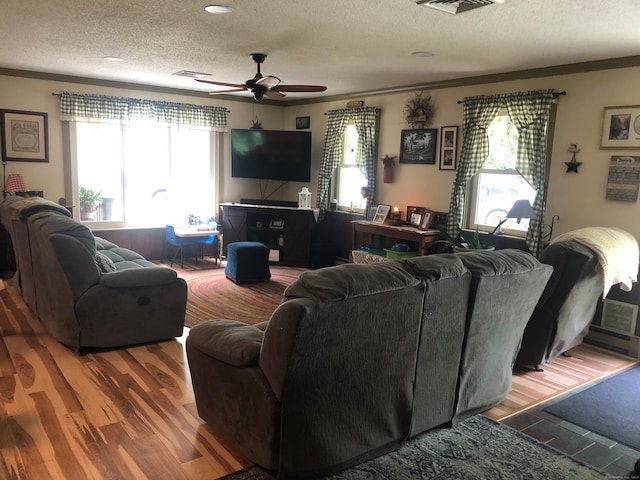 living room featuring a textured ceiling, ceiling fan, hardwood / wood-style floors, and crown molding