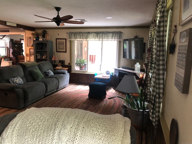 living room featuring a textured ceiling, ceiling fan, wood-type flooring, and ornamental molding