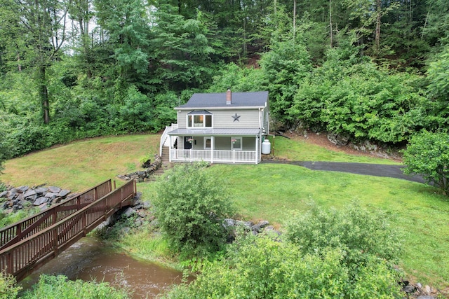 rear view of property with covered porch and a lawn