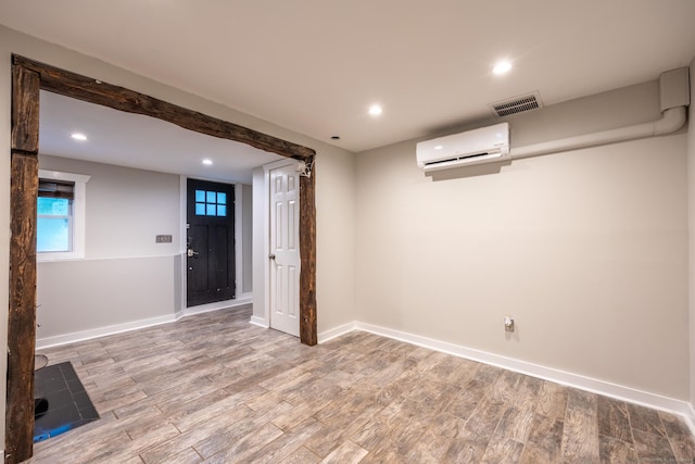 basement with an AC wall unit and light hardwood / wood-style floors