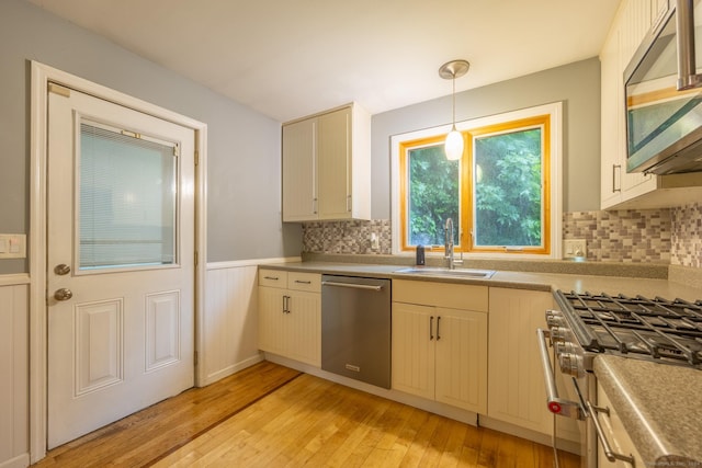 kitchen featuring light hardwood / wood-style floors, pendant lighting, decorative backsplash, sink, and stainless steel appliances