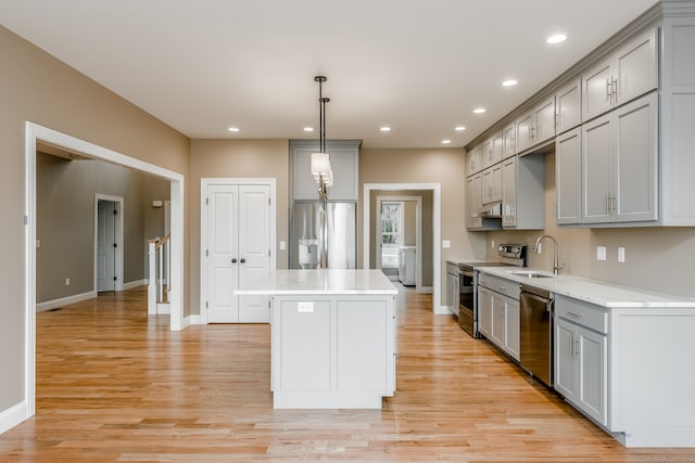 kitchen featuring gray cabinets, stainless steel appliances, pendant lighting, a kitchen island, and light hardwood / wood-style flooring