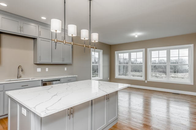 kitchen with hanging light fixtures, a center island, gray cabinets, and light wood-type flooring