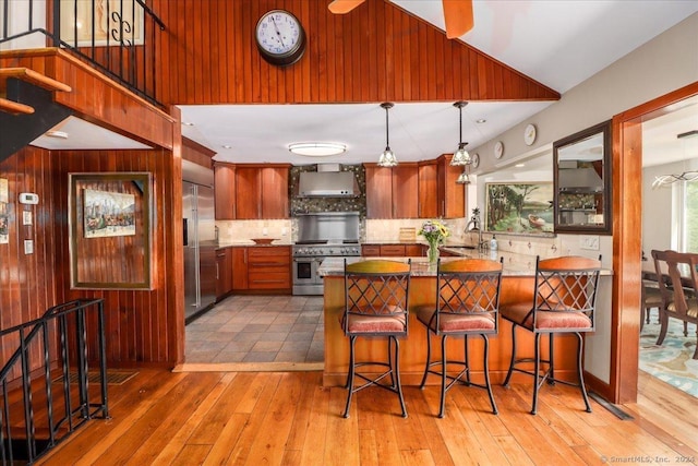 kitchen featuring pendant lighting, hardwood / wood-style floors, high end appliances, tasteful backsplash, and kitchen peninsula