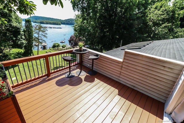 deck with a water view and a lawn