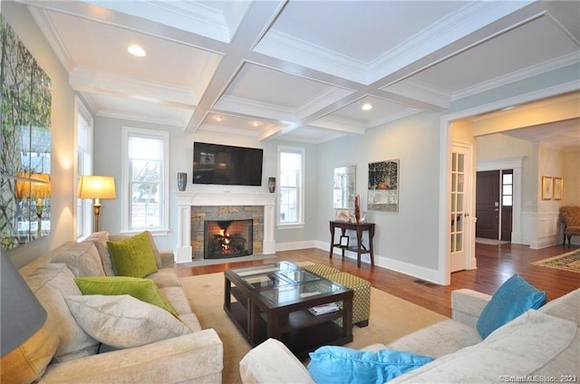 living room featuring plenty of natural light, a stone fireplace, hardwood / wood-style floors, and coffered ceiling