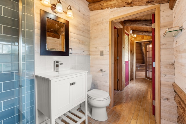 bathroom featuring vanity, wood-type flooring, vaulted ceiling with beams, wood walls, and toilet