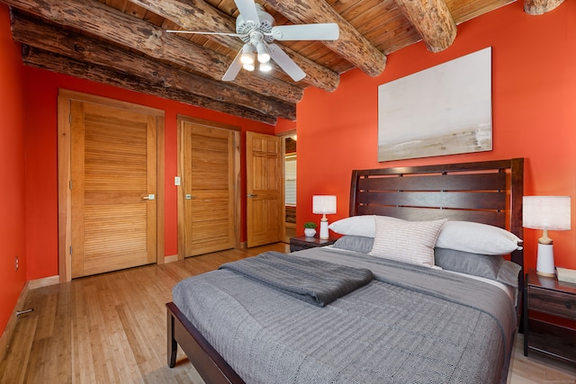 bedroom featuring multiple closets, ceiling fan, wooden ceiling, hardwood / wood-style floors, and beam ceiling