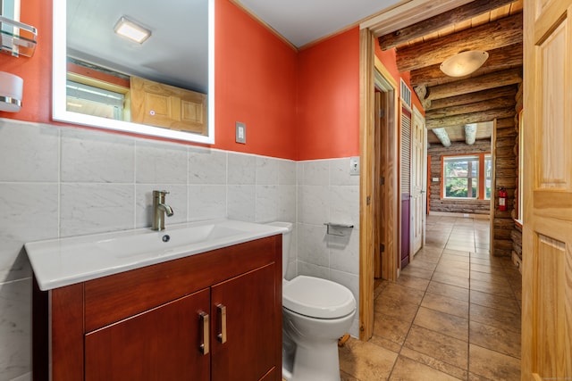 bathroom with toilet, vanity, tile patterned flooring, and log walls