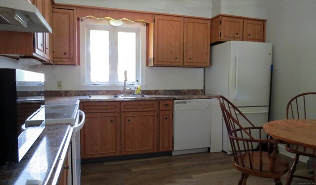 kitchen featuring sink, dark hardwood / wood-style flooring, wall chimney range hood, and white appliances