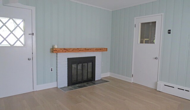 unfurnished living room featuring ornamental molding, hardwood / wood-style flooring, a brick fireplace, and baseboard heating