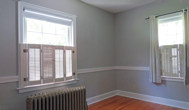 unfurnished room with wood-type flooring and radiator heating unit