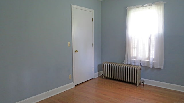 unfurnished room featuring radiator, hardwood / wood-style floors, and a wealth of natural light