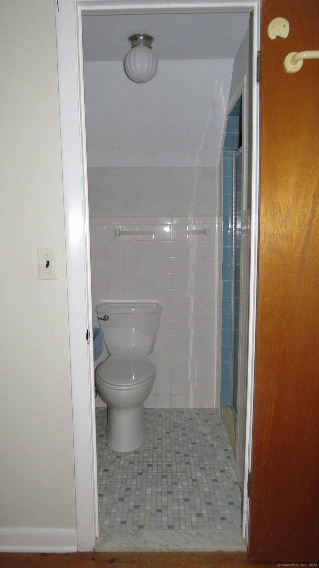 bathroom featuring tile patterned floors, walk in shower, tile walls, and toilet