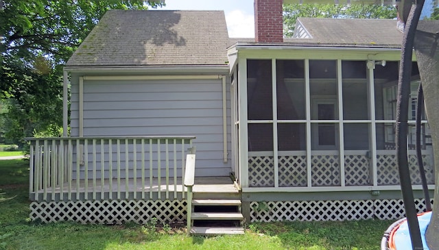 rear view of property featuring a sunroom and a deck