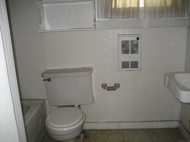 bathroom featuring tile patterned floors, toilet, tile walls, a tub, and heating unit