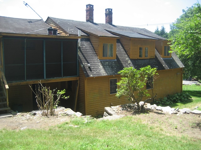 rear view of property with a lawn and a sunroom