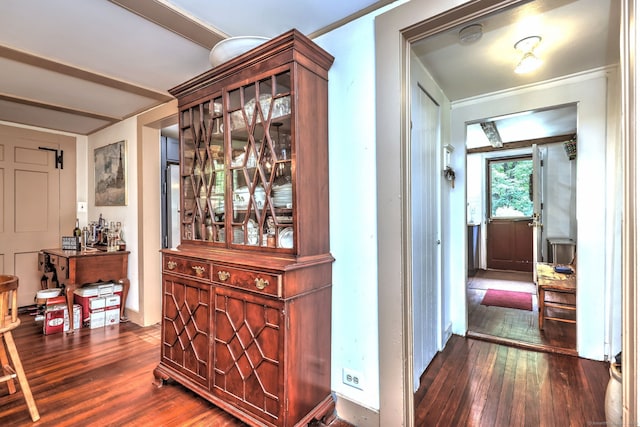 hallway featuring beam ceiling, dark wood-type flooring, and ornamental molding