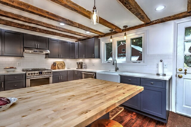 kitchen with wood counters, beamed ceiling, appliances with stainless steel finishes, decorative backsplash, and decorative light fixtures