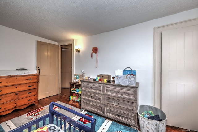 bedroom with dark hardwood / wood-style floors and a textured ceiling